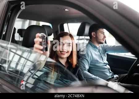 Junges Paar sitzt in einem Autohaus in ihrem neuen Auto Stockfoto