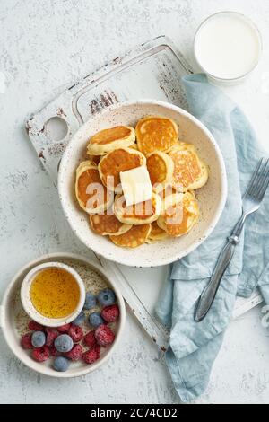 Pfannkuchen, Müsli, winzig dünne, lustige Krümel, Kinderessen. Frühstück mit Getränk, weißer Tisch Stockfoto