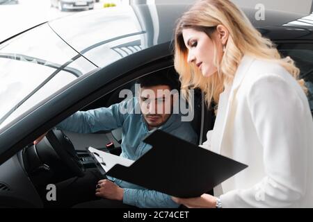 Autoverkäuferin zeigt Dokumente für männliche Kunden Stockfoto