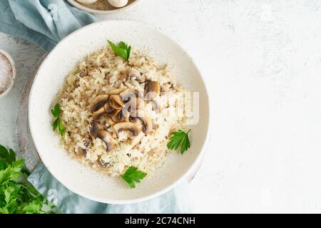 Risotto mit Pilzen auf dem Teller. Reisbrei mit Pilzen und Petersilie Stockfoto