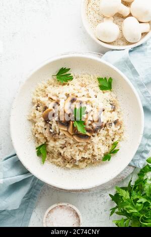 Risotto mit Pilzen auf dem Teller. Reisbrei mit Pilzen und Petersilie Stockfoto