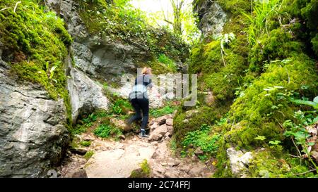 Eine Person, die den Rocky-Wanderweg durch eine enge Schlucht im Wald des Ebbor Gorge National Nature Reserve wandert. Wookey Hole, Wells, Großbritannien Stockfoto