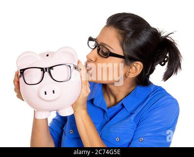Porträt einer jungen lächelnden Frau mit Brille halten geben einen Kuss auf ein Sparschwein, isoliert auf weißem Hintergrund. Stockfoto