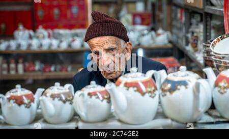 Isfahan, Iran - Mai 2019: Alter Iraner, der in seinem Geschäft im Großen Basar von Isfahan, Iran, Teekannen verkauft Stockfoto