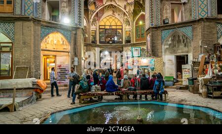 Kashan, Iran - Mai 2019: Gruppe von Touristen, die in der Aminoddole Caravanserai des Großen Basars von Kashan, Iran mit Backstein Wabendekoren ruhen, bedeckt Stockfoto