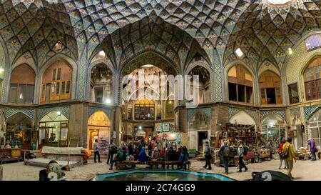 Kashan, Iran - Mai 2019: Gruppe von Touristen, die in der Aminoddole Caravanserai des Großen Basars von Kashan, Iran mit Backstein Wabendekoren ruhen, bedeckt Stockfoto