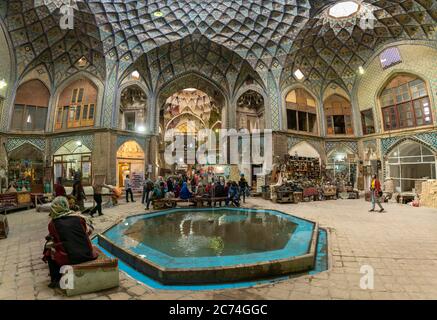 Kashan, Iran - Mai 2019: Gruppe von Touristen, die unter dem Dach von Aminoddole Caravanserai des Großen Basars von Kashan, mit Backstein Wabendekore ruhen, c Stockfoto