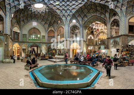 Kashan, Iran - Mai 2019: Gruppe von Touristen, die unter dem Dach von Aminoddole Caravanserai des Großen Basars von Kashan, mit Backstein Wabendekore ruhen, c Stockfoto