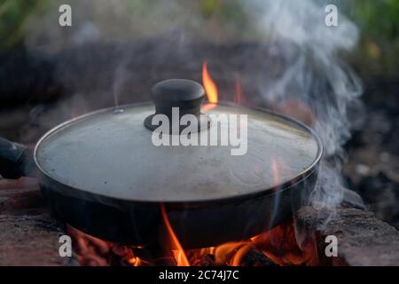 Gegrillte Hackfleischwürste, in einer Pfanne in der Nähe des Feuers liegen Stockfoto