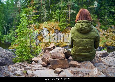 Hinter der jungen Frau bewundert die nördliche Natur. Person, die auf Felsen, Steinen, Rückansicht, Stockfoto