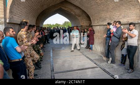 Isfahan, Iran - Mai 2019: Iraner singen und unterhalten sich unter der Khaju Brücke über den Zayandeh Fluss Stockfoto