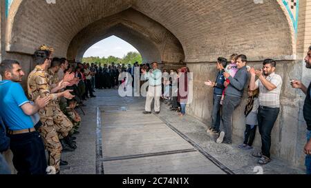 Isfahan, Iran - Mai 2019: Iraner singen und unterhalten sich unter der Khaju Brücke über den Zayandeh Fluss Stockfoto