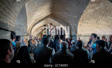 Isfahan, Iran - Mai 2019: Iraner singen und unterhalten sich unter der Khaju Brücke über den Zayandeh Fluss Stockfoto