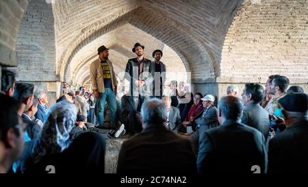 Isfahan, Iran - Mai 2019: Iraner singen und unterhalten sich unter der Khaju Brücke über den Zayandeh Fluss Stockfoto