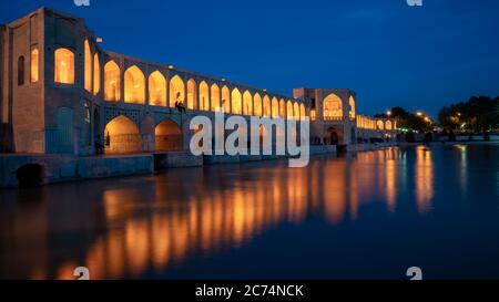 Isfahan, Iran - Mai 2019: Khaju Brücke über Zayandeh Fluss in der Dämmerung mit Lichtern während der blauen Stunde Stockfoto