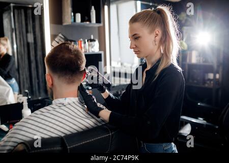 Porträt eines Mannes in Barbershop, rasieren und schneiden von Barber Mädchen Stockfoto