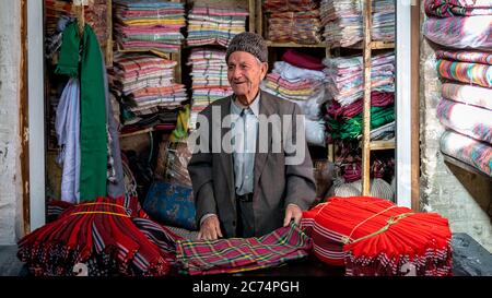 Isfahan, Iran - Mai 2019: Der alte iranische Mann verkauft in seinem kleinen Laden im Großen Basar von Isfahan Textilien Stockfoto