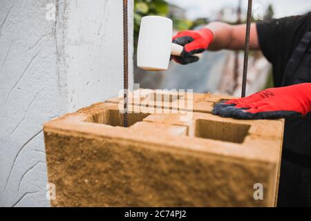 Ein professioneller Maurer baut Säulen für einen Steinzaun aus Zementblöcken - Stützzaun eines privaten Geländes Stockfoto