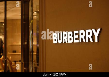 Nahaufnahme DES BURBERRY-Logos an der Außenwand des Ladens bei Nacht. Eine britische Luxusmodemarke. Hintergrund verwischen. Stockfoto