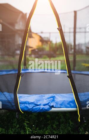 Trampolin im Hinterhof - Eingang durch ein offenes Netz - Outdoor-Aktivitäten und Unterhaltung für die ganze Familie Stockfoto