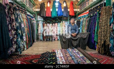 Isfahan, Iran - Mai 2019: Iranischer Mann, der in seinem kleinen Laden im Großen Basar von Isfahan Textilien verkauft Stockfoto