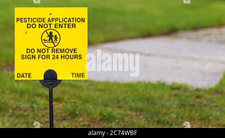 Ein gelbes Schild Platz auf einem Wohnrasen liest Pestizid Anwendung, nicht für 24 Stunden eingeben. Stockfoto