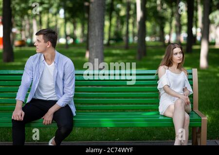 Familienkonflikt. Junger Mann und Frau sitzen auf der Bank im Park getrennt voneinander Stockfoto