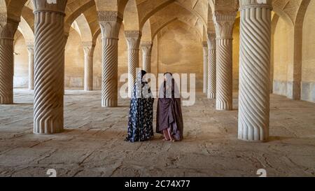 Shiraz, Iran - Mai 2019: Zwei iranische Frauen sprechen im Gebetsraum der Vakil Moschee mit Säulen. Vakil bedeutet Regent, Titel von Karim Khan, Gründer von Za Stockfoto