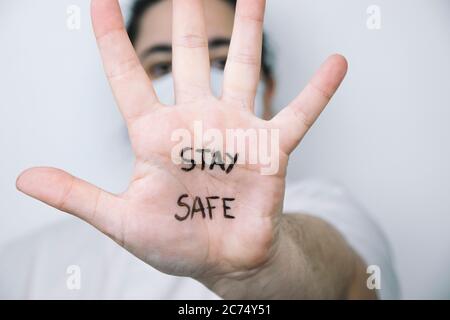 Frau auf einer Seite mit der Hand nach vorne mit dem Satz "zu Hause" auf der Handfläche geschrieben. Coronavirus-Konzept. Stockfoto