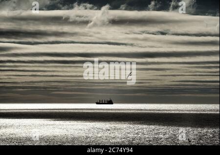 Ein Frachtschiff sitzt am Horizont vor der Nordostküste nahe Whitley Bay. Stockfoto