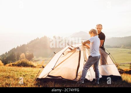 Vater und Sohn Installation Zelt auf Waldlichtung.Trekking mit Kindern Konzept Bild Stockfoto