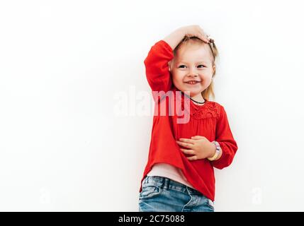 Kleines Mädchen gekleidet rote Bluse auf dem weißen Hintergrund. Verwirrte Emotionen Konzept Bild. Stockfoto