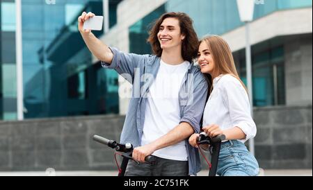 Freunde, die auf motorisierten Kick Scootern fahren, Selfies machen Stockfoto