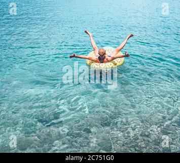 Mann entspannt beim Schwimmen auf aufblasbaren Ananas Pool Ring in kristallklarem Meerwasser. Sorgloses Urlaubskonzept Bild. Stockfoto