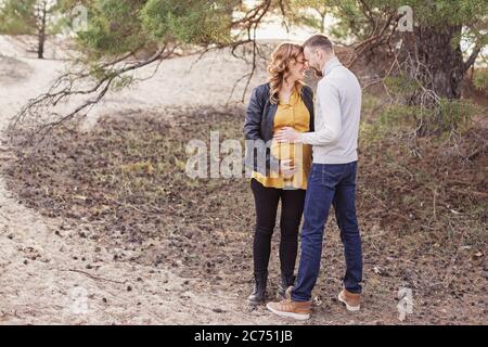 Junge glückliche Paar erwartet Baby auf ihrem Spaziergang im Park Stockfoto