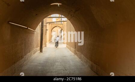 Yazd, Iran - Mai 2019: Kind auf einem Fahrrad fahren in der engen Straße der Altstadt Yazd Stockfoto