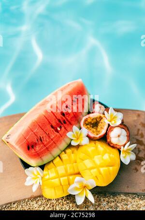 Tropische Früchte und Blumen Stillleben in der Nähe des Pools: Wassermelone, Mango, Mangostan, Passionsfrucht Stockfoto