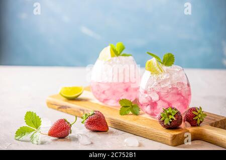 Pink Cocktail mit Limette, zerkleinert Eis, Erdbeeren und Minze auf dem hellen Hintergrund, selektive Fokus Bild, Kopie Gewürz für Sie Text, Sommerurlaub ein Stockfoto