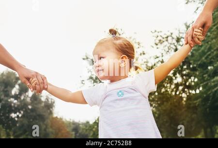 Nettes kleines Mädchen nehmen Hände mit ihren Verwandten Menschen. Walking with Kids Konzept Bild. Stockfoto