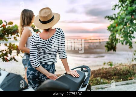 Zwei Freundinnen Reisende Blick auf Sonnenuntergang über dem Meer während ihrer motojorney Stockfoto