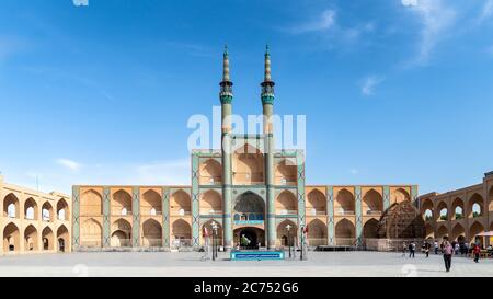 Yazd, Iran - Mai 2019: Jameh Moschee Eingangstor mit Minaretten mit iranischen Menschen und Touristen herumlaufen Stockfoto