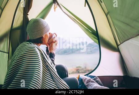 Morgen im lager temt.Frau mit einer Tasse heißen Tee sitzen im Zelt Stockfoto