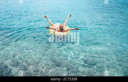 Mann entspannt beim Schwimmen auf aufblasbaren Ananas Pool Ring in kristallklarem Meerwasser. Sorgloses Urlaubskonzept Bild. Stockfoto