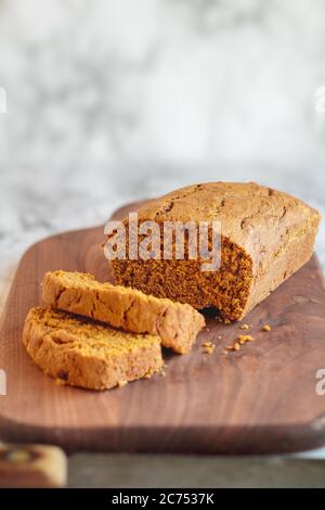 Frisch gebackenes, hausgemachtes Kürbisbrot, in Scheiben geschnitten auf einem Schneidebrett mit altem Messer. Selektiver Fokus mit unscharfem Vorder- und Hintergrund. Stockfoto