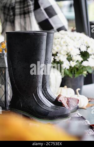 Schwarze Gummi-Regenstiefel oder Gummistiefel, sitzen auf der Veranda für den Herbst dekoriert. Stockfoto