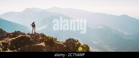 Bergwanderer mit Rucksack winzige Figur Aufenthalt auf Berggipfel mit schönem Panorama Stockfoto