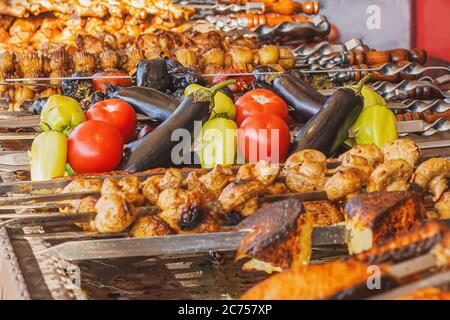 Riesige Straße Grill mit verschiedenen Arten von Fleisch und Gemüse auf Spieße mit selektivem Fokus. Rohes und gebratenes Gemüse und Fleisch auf dem Straßenmarkt Stockfoto