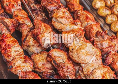 Saftig frisch gebratenes Schweinefleisch auf Spieße auf einem Holzkohlegrill. Seitenansicht von gebackenem, ruddeligen Fleisch auf einer Theke in einem Straßenmarkt. Schweinekebab im Barbec gekocht Stockfoto