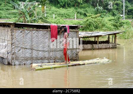 Kamrup, Assam, Indien. Juli 2020. Ein Mädchen trocknet Tuch in einem überfluteten Gebiet, das auf einem Floß steht, in einem von der Flut betroffenen Dorf, im Kamrup Bezirk von Assam. Kredit: David Talukdar/ZUMA Wire/Alamy Live Nachrichten Stockfoto