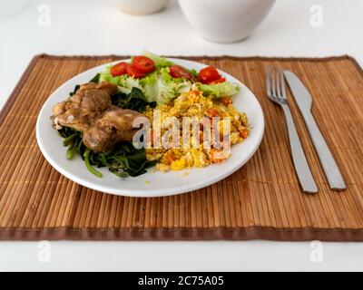 Weißes Geschirr, mit Salat, Tomaten, Brokkoli, marokkanischem Couscous und im Ofen gebratenen Hähnchenfeile, auf Strohbasis auf weißem Tisch, Rio de Janeiro, Br Stockfoto